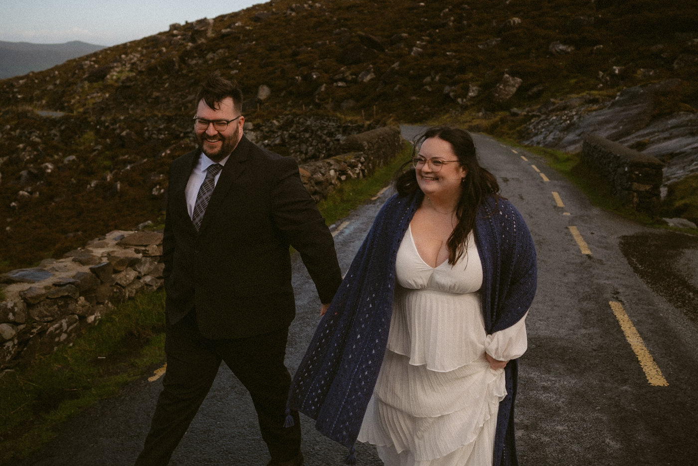 An elopement couple laughing near Conor Pass Waterfall in the Dingle Peninsula