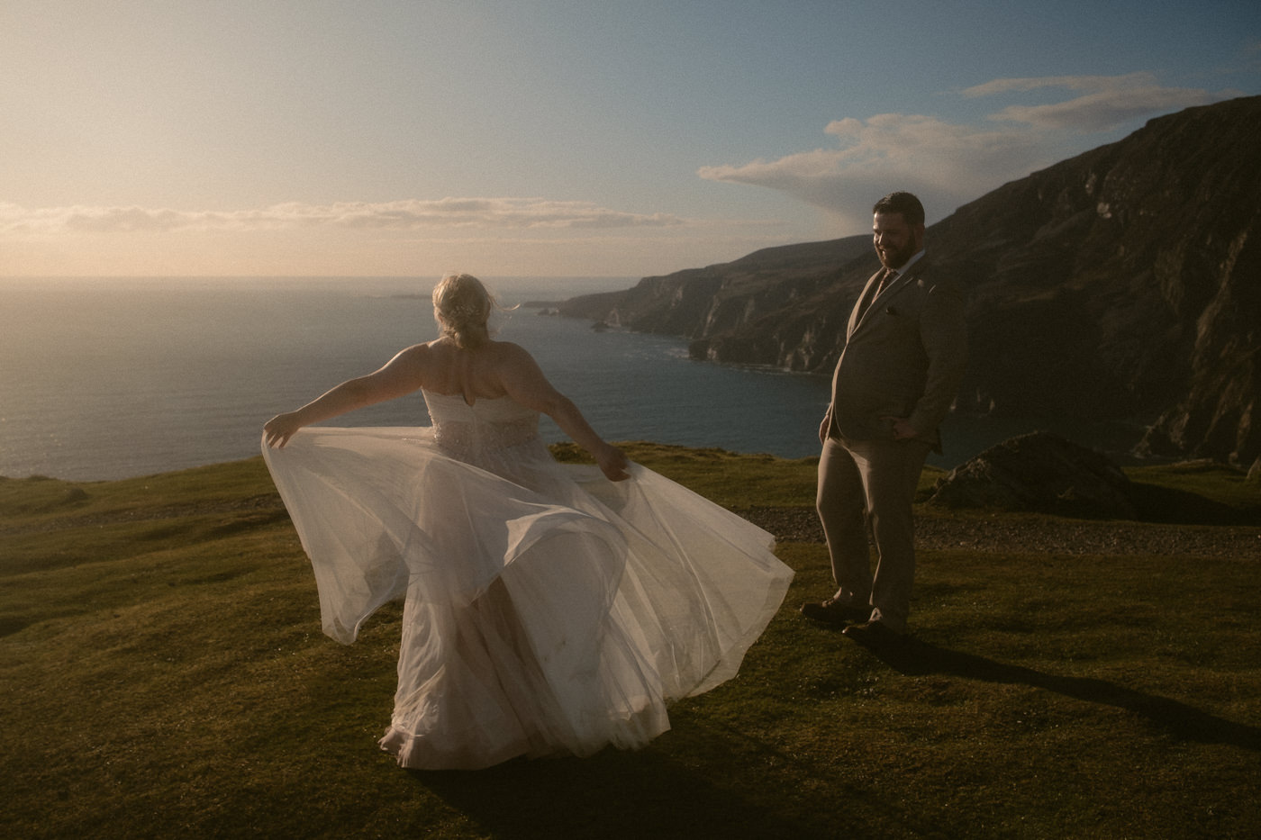 A bride dances in front of her husband at the Slieve League cliffs