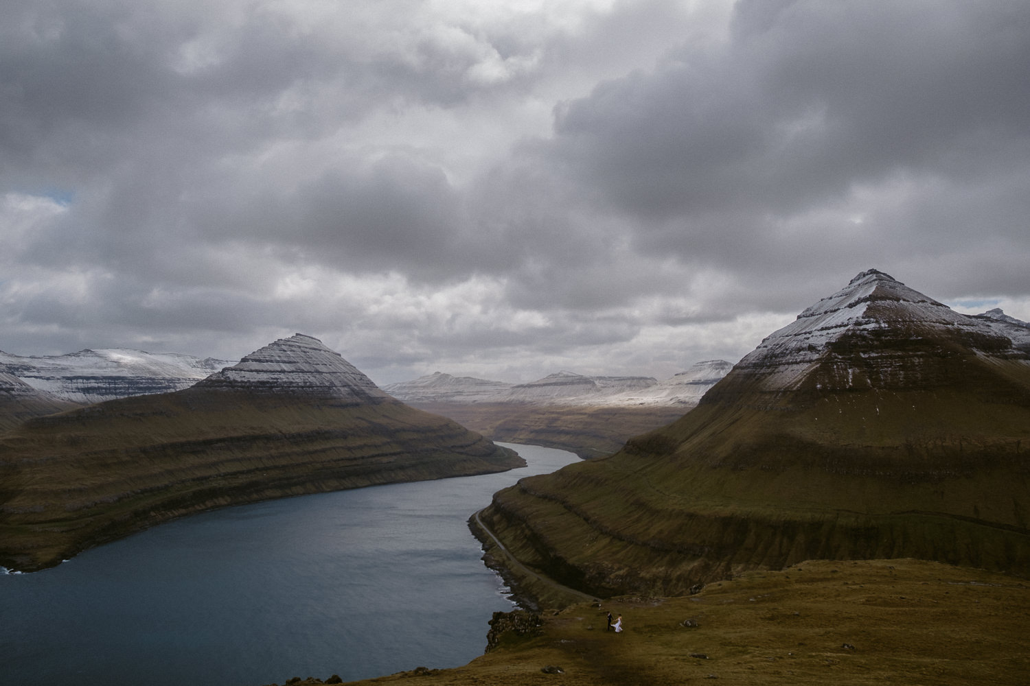 Wide-angle short of a couple eloping in front of a breathtaking landscape at Hvíthamar viewpoint in the Faroe Islands