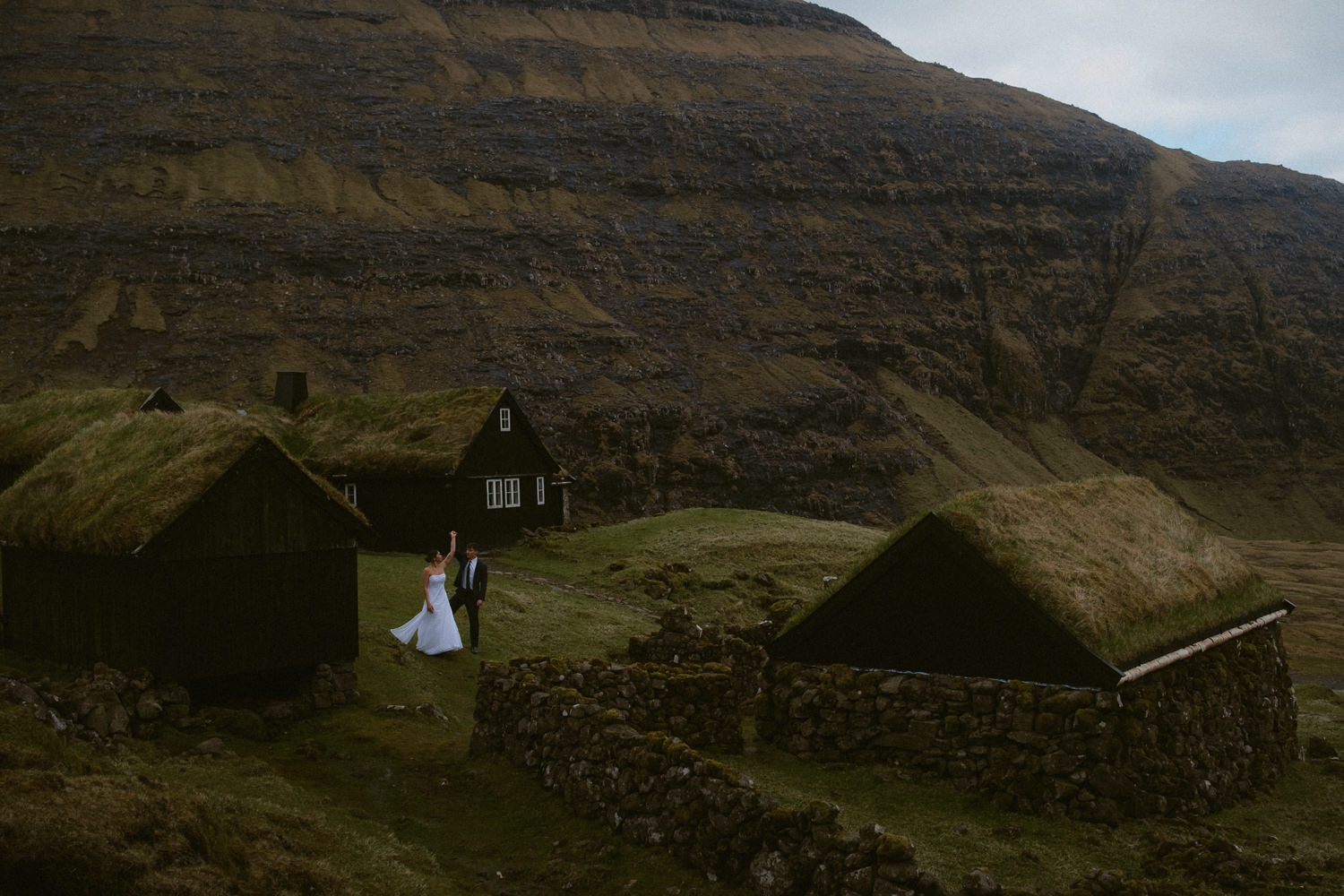 Faroe Islands elopement couple dancing between turf houses in an ancient village in the Faroe Islands