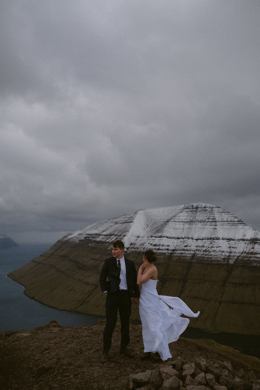 Faroe Islands elopement couple walking through wind and rain on Klakkur Mountain in May
