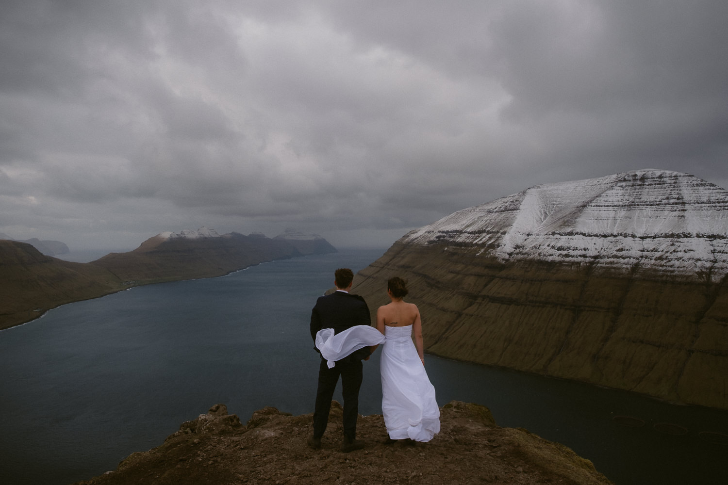 Elopement wedding dress blowing in the wind on Klakkur Mountain in the Faroe Islands