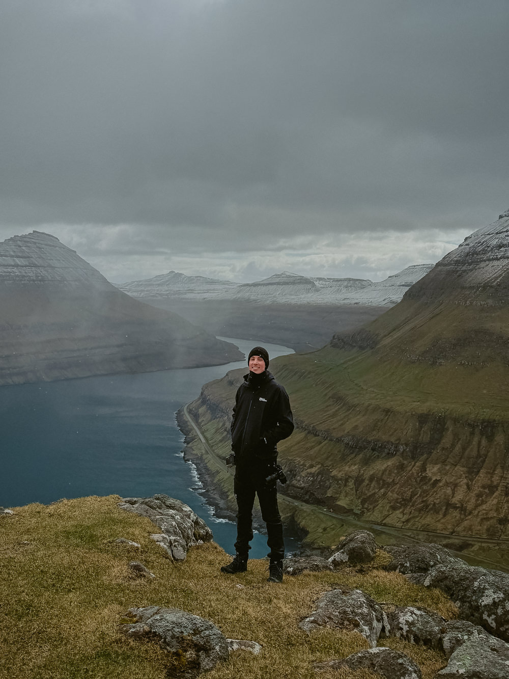 Photo of a Faroe Islands Elopement Photographer in front of a vast fjord with mountains in the background